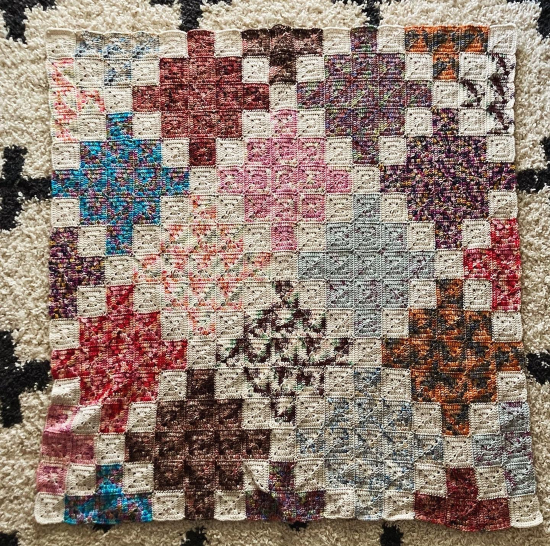 crochet quilt style blanket uses solid granny squares to create cross patterns across the blanket