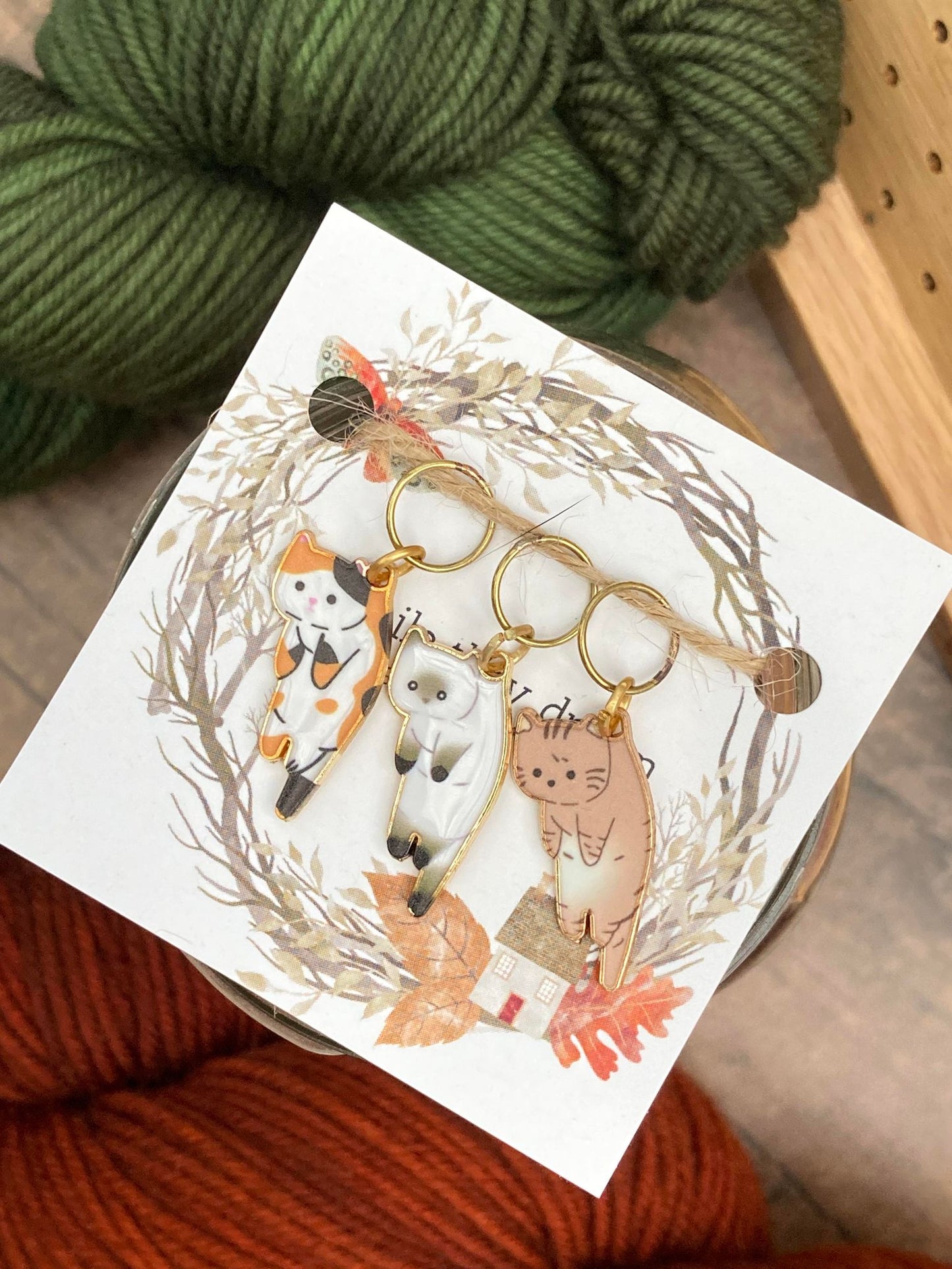 3 cat stitch markers, one calico, one siamese, and one brown tabby