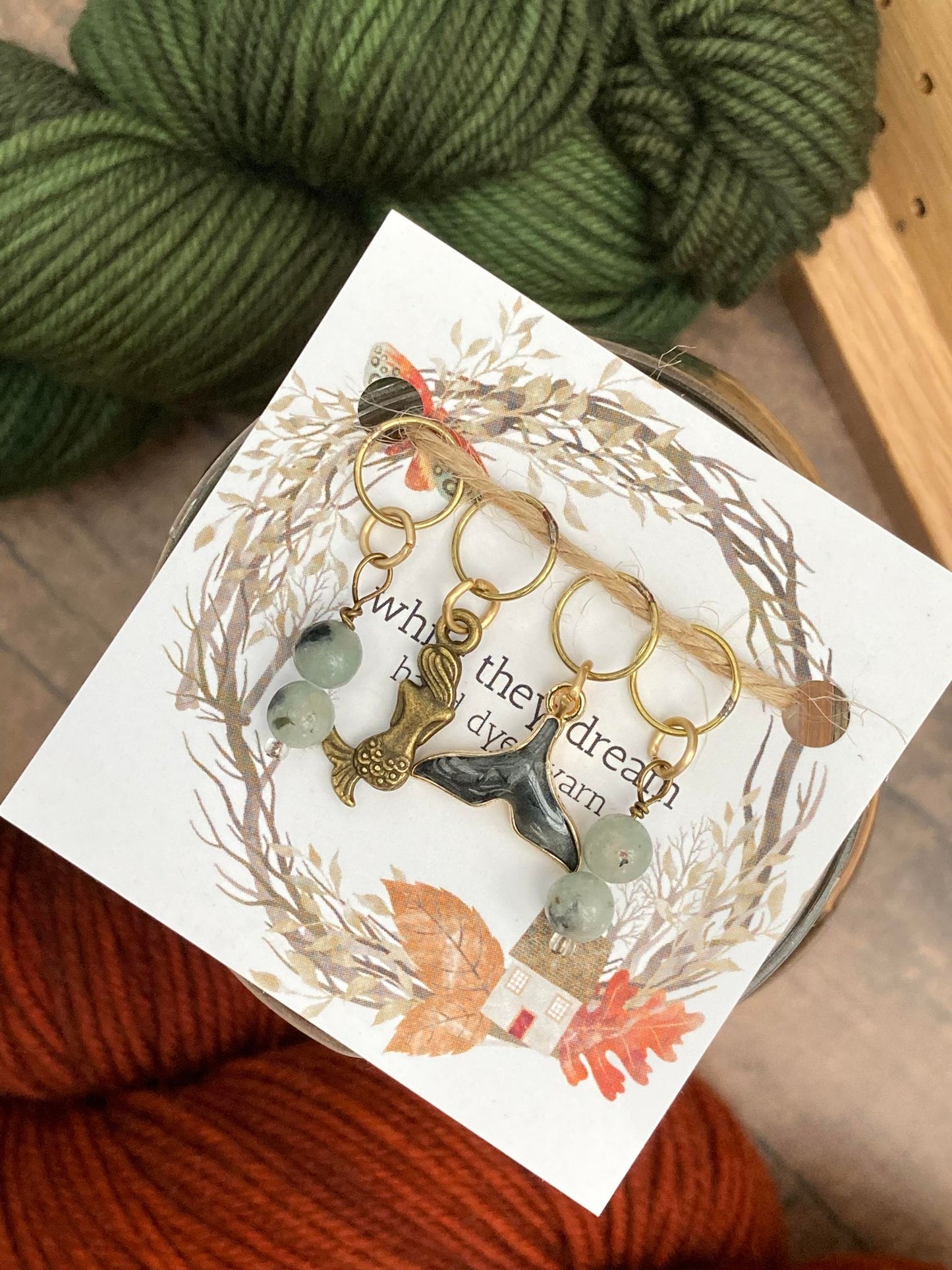 gemstone stitch markers paired with a bronze mermaid stitch marker and a black gemstone whale tail stitch marker