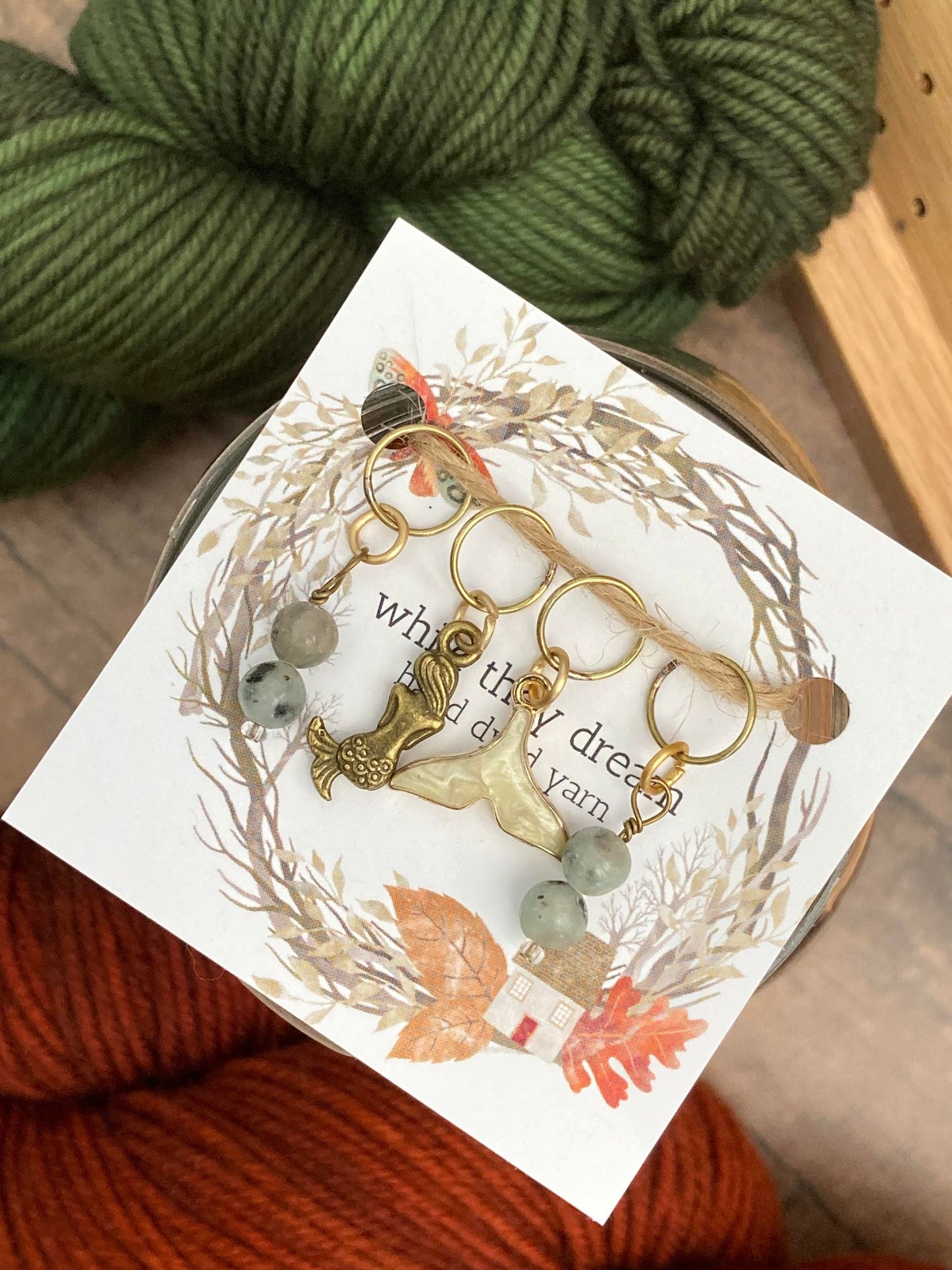 gemstone stich markers paired with a bronze mermaid stitch marker and a gemstone whale tail stitch marker