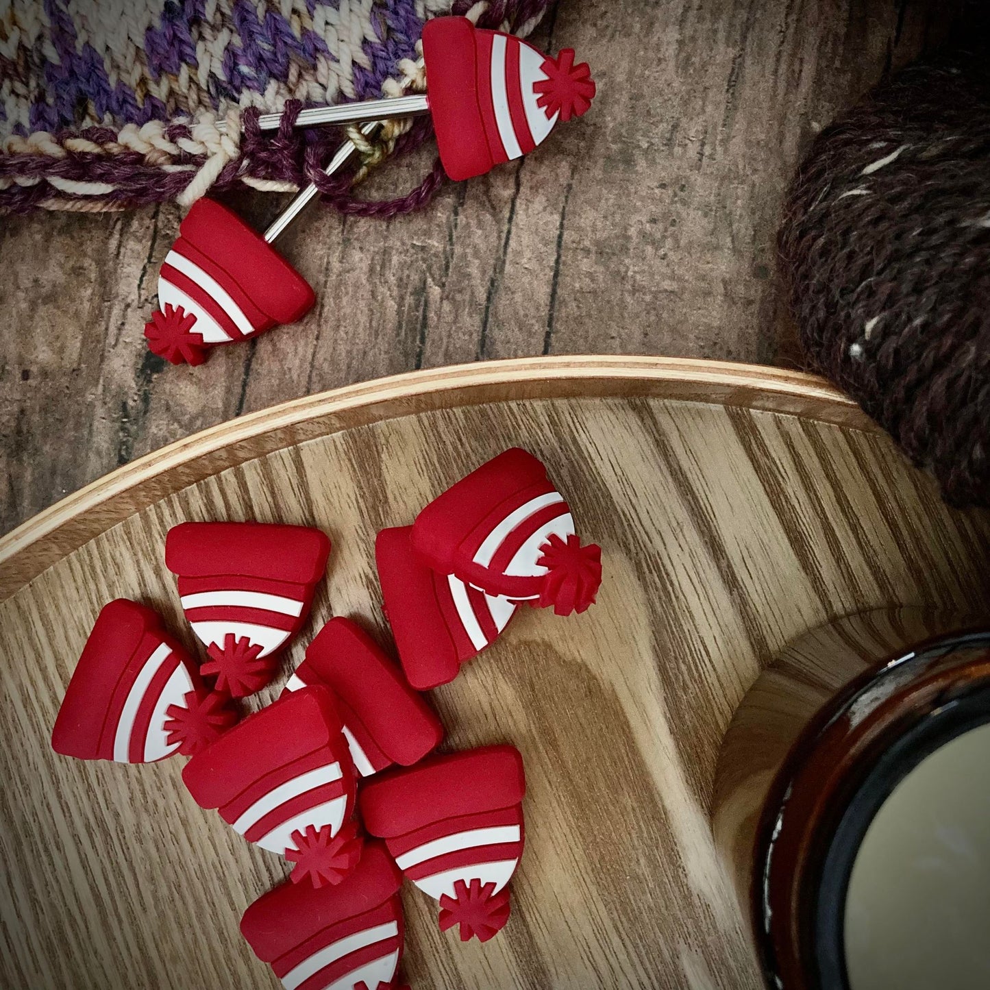 Red knit hat needle stoppers with white stripes and a pom pom