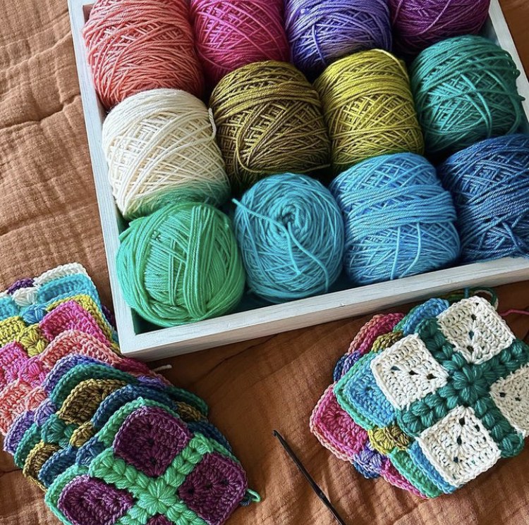 crochet granny squares with a puff stitch cross detail are put together to form a quilt style patchwork blanket