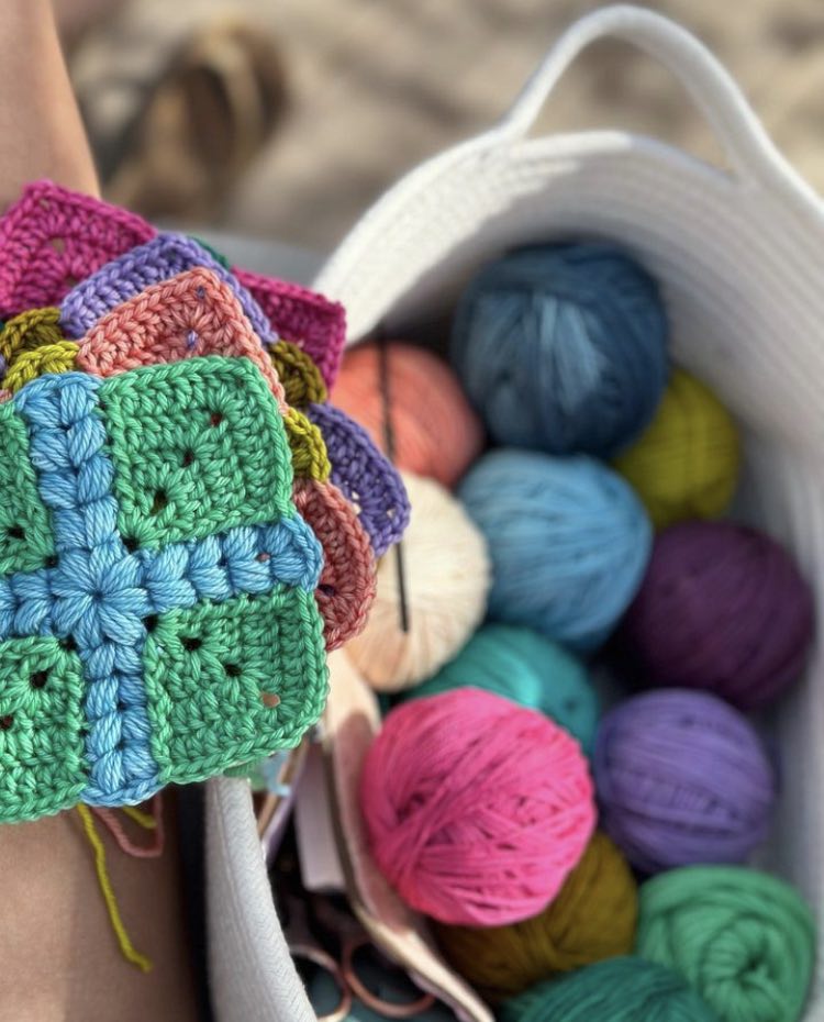 crochet granny squares with a puff stitch cross detail are put together to form a quilt style patchwork blanket