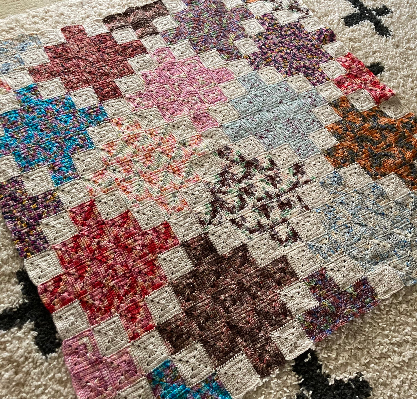 crochet quilt style blanket uses solid granny squares to create cross patterns across the blanket