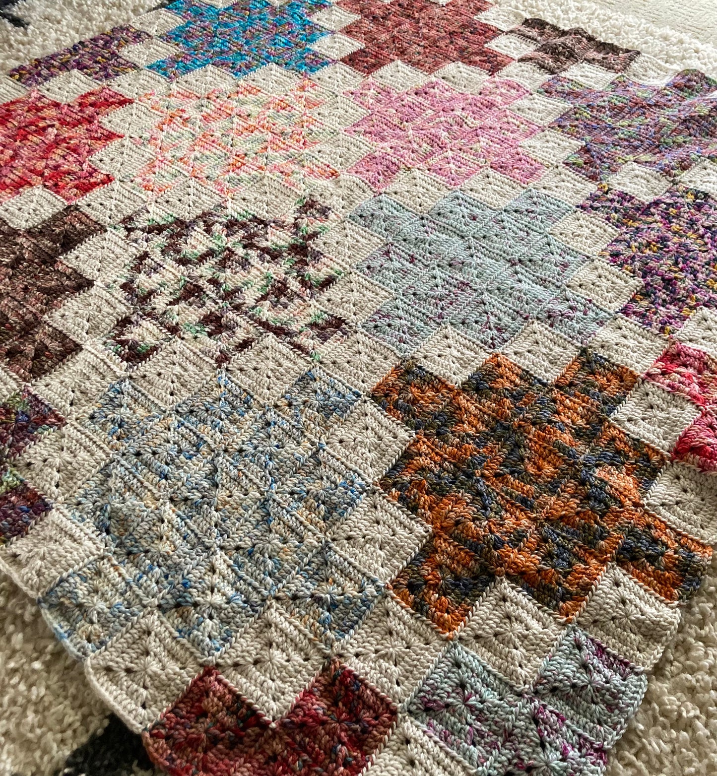 crochet quilt style blanket uses solid granny squares to create cross patterns across the blanket
