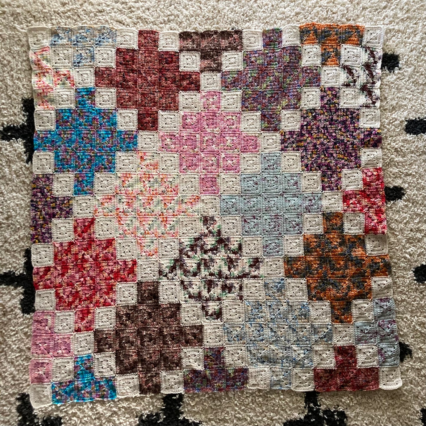 crochet quilt style blanket uses solid granny squares to create cross patterns across the blanket
