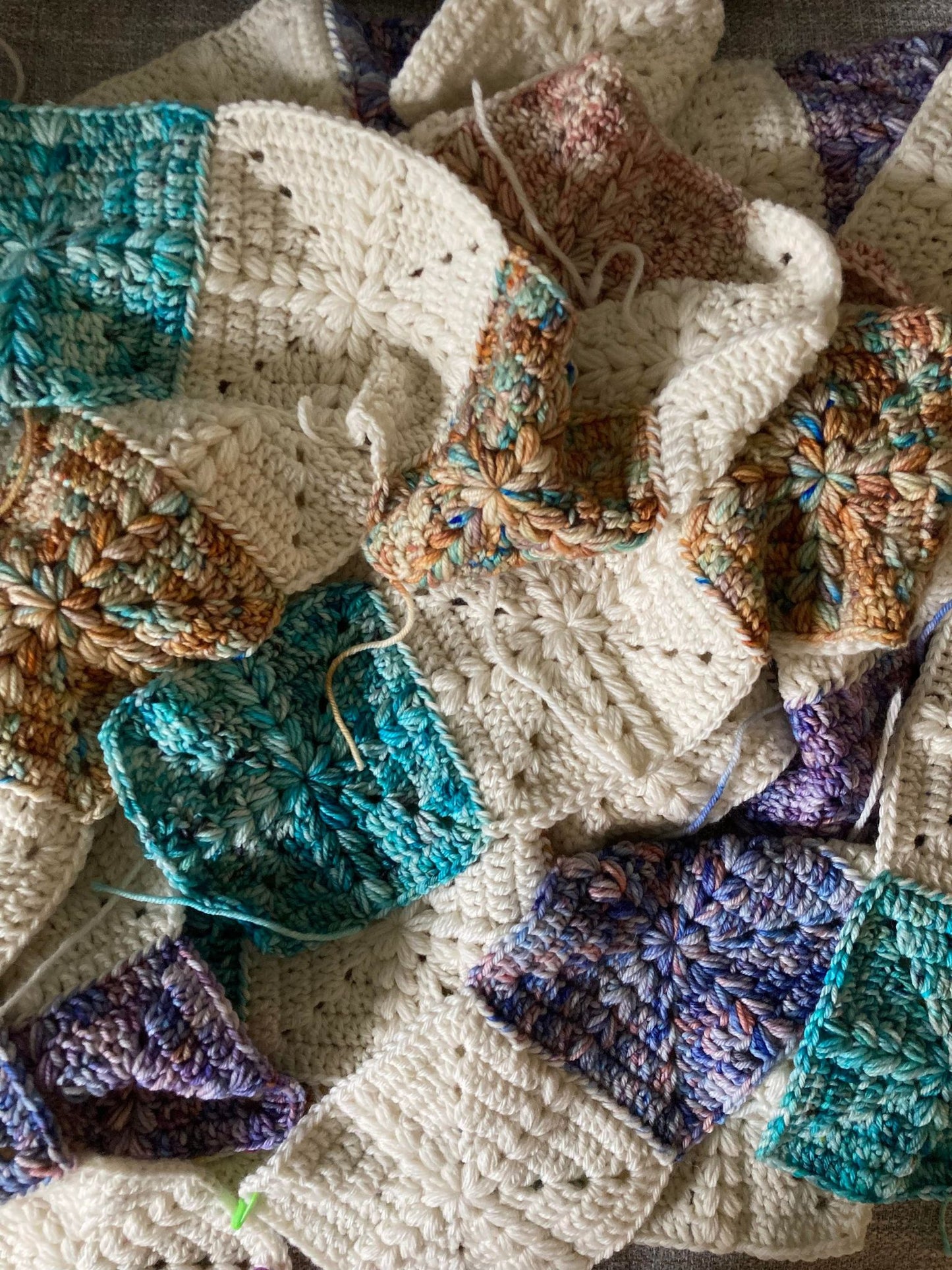 crochet granny squares with a puff stitch cross detail are put together to form a quilt style patchwork blanket