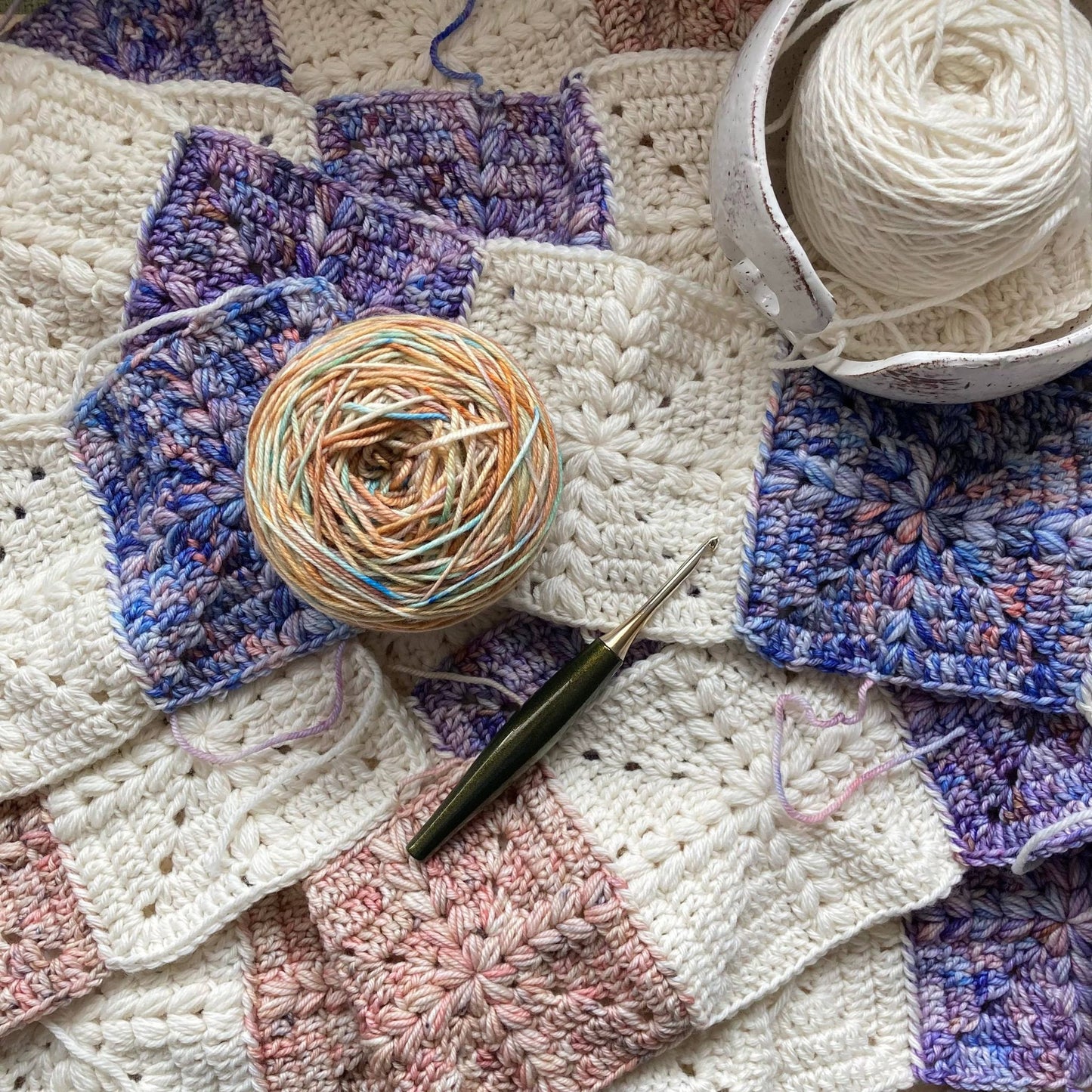 crochet granny squares with a puff stitch cross detail are put together to form a quilt style patchwork blanket