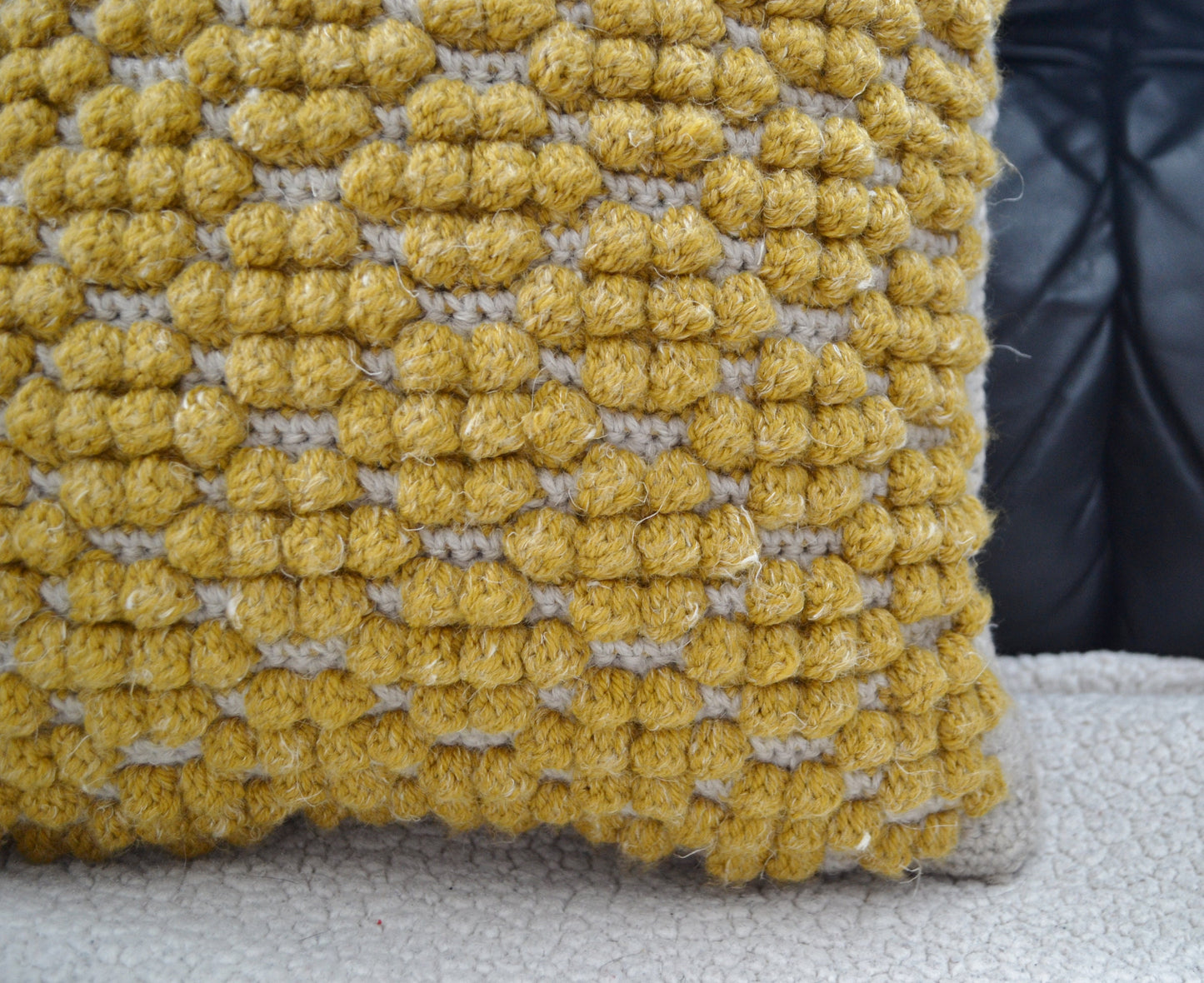 crochet pillow cover with crochet bobble stitches that look like honeycomb