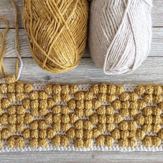 crochet pillow cover with crochet bobble stitches that look like honeycomb
