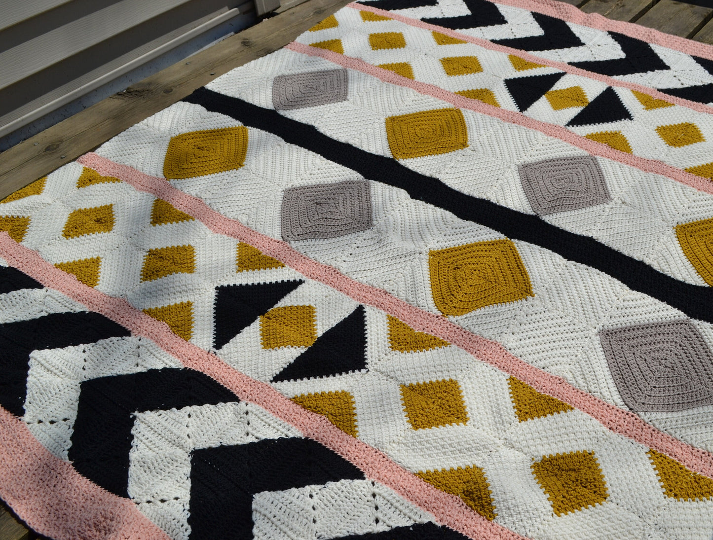 A crochet quilt made from various crochet squares and vertical strips of various textures to create a crochet quilt style blanket.