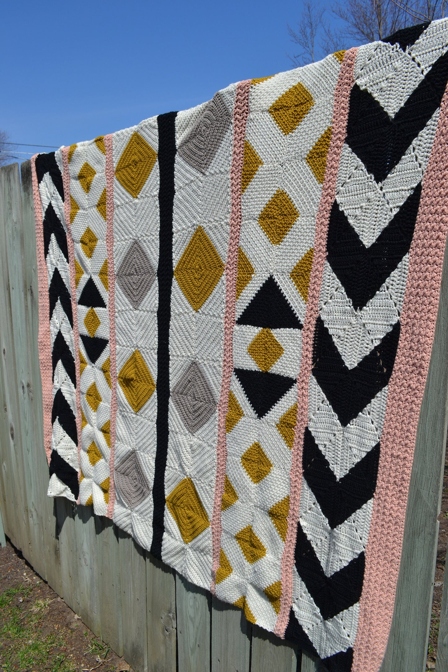 A crochet quilt made from various crochet squares and vertical strips of various textures to create a crochet quilt style blanket.