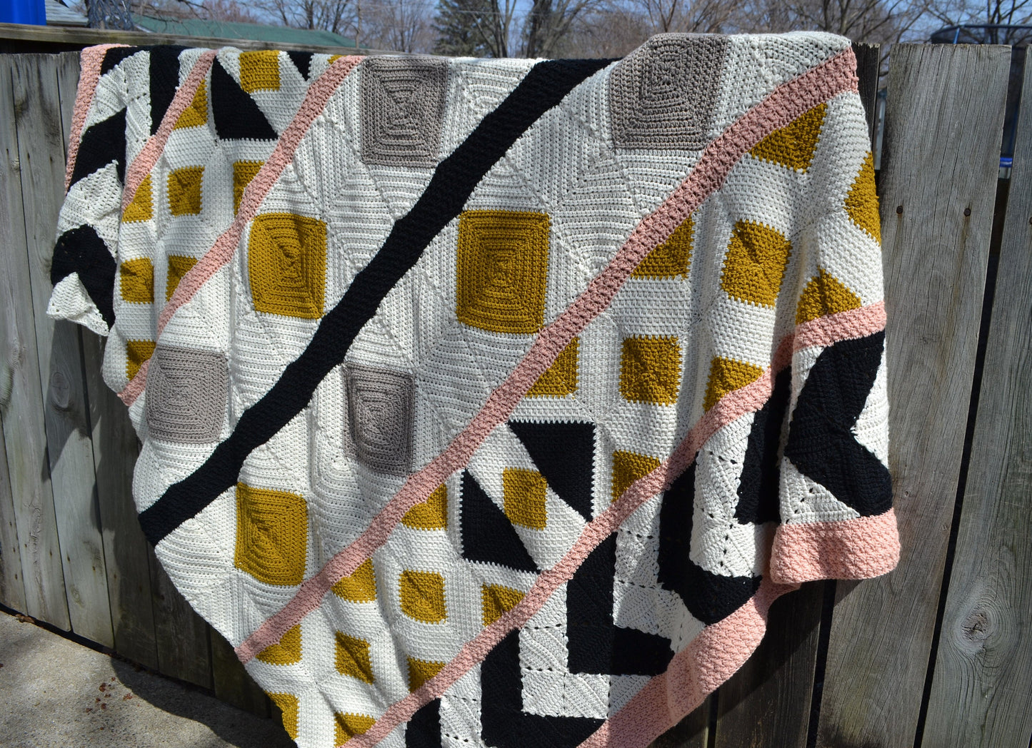 A crochet quilt made from various crochet squares and vertical strips of various textures to create a crochet quilt style blanket.