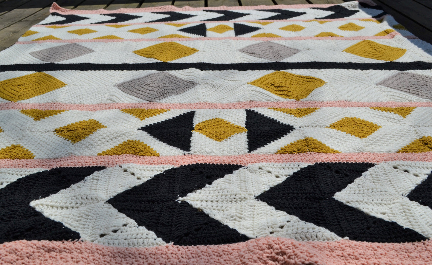 A crochet quilt made from various crochet squares and vertical strips of various textures to create a crochet quilt style blanket.