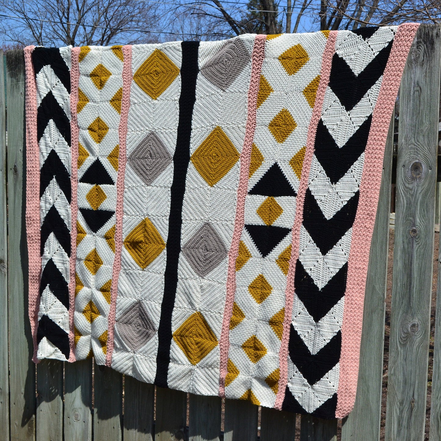 A crochet quilt made from various crochet squares and vertical strips of various textures to create a crochet quilt style blanket.