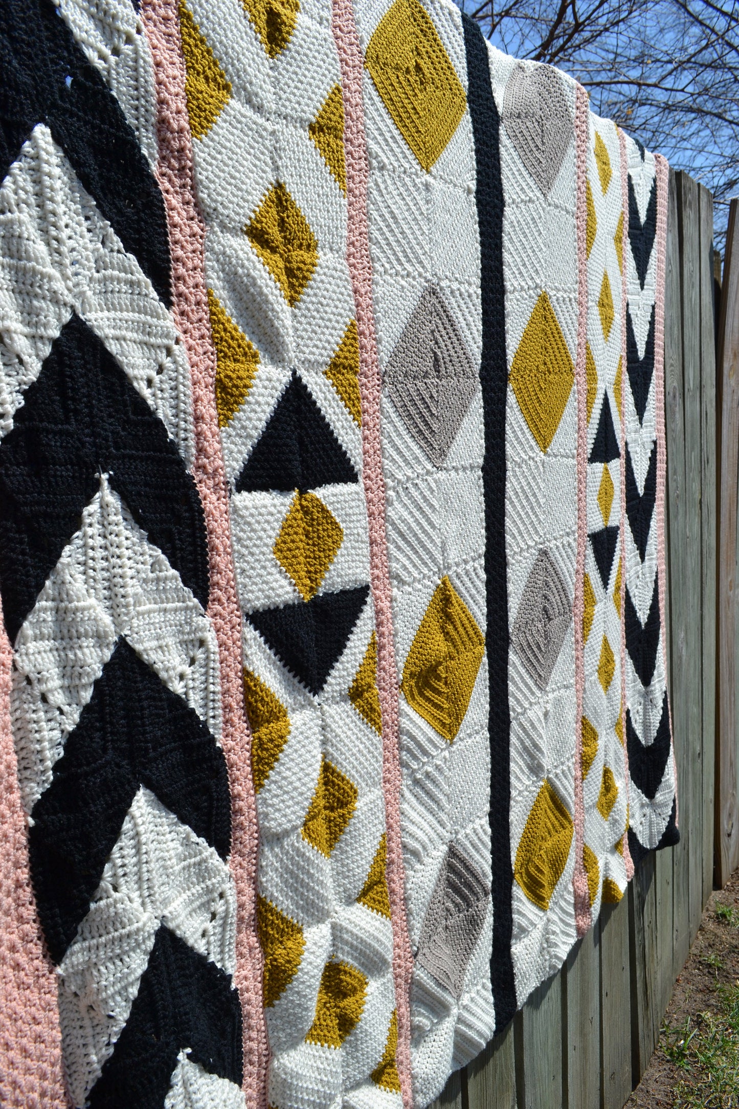 A crochet quilt made from various crochet squares and vertical strips of various textures to create a crochet quilt style blanket.