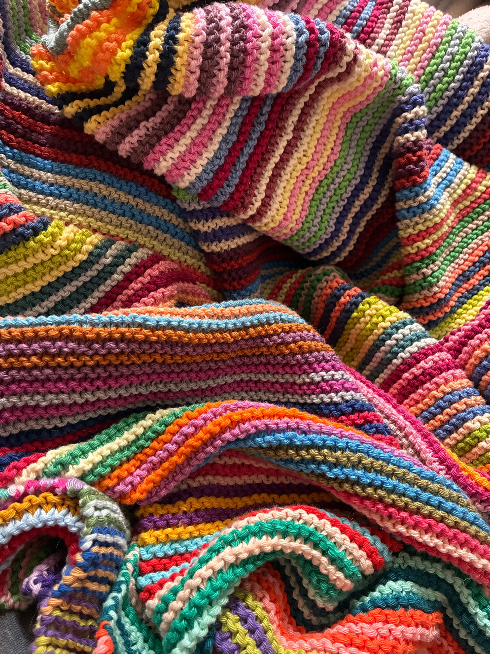 Knit garter stitch blanket using a rainbow of colors in Scheepjes Cahlista yarn