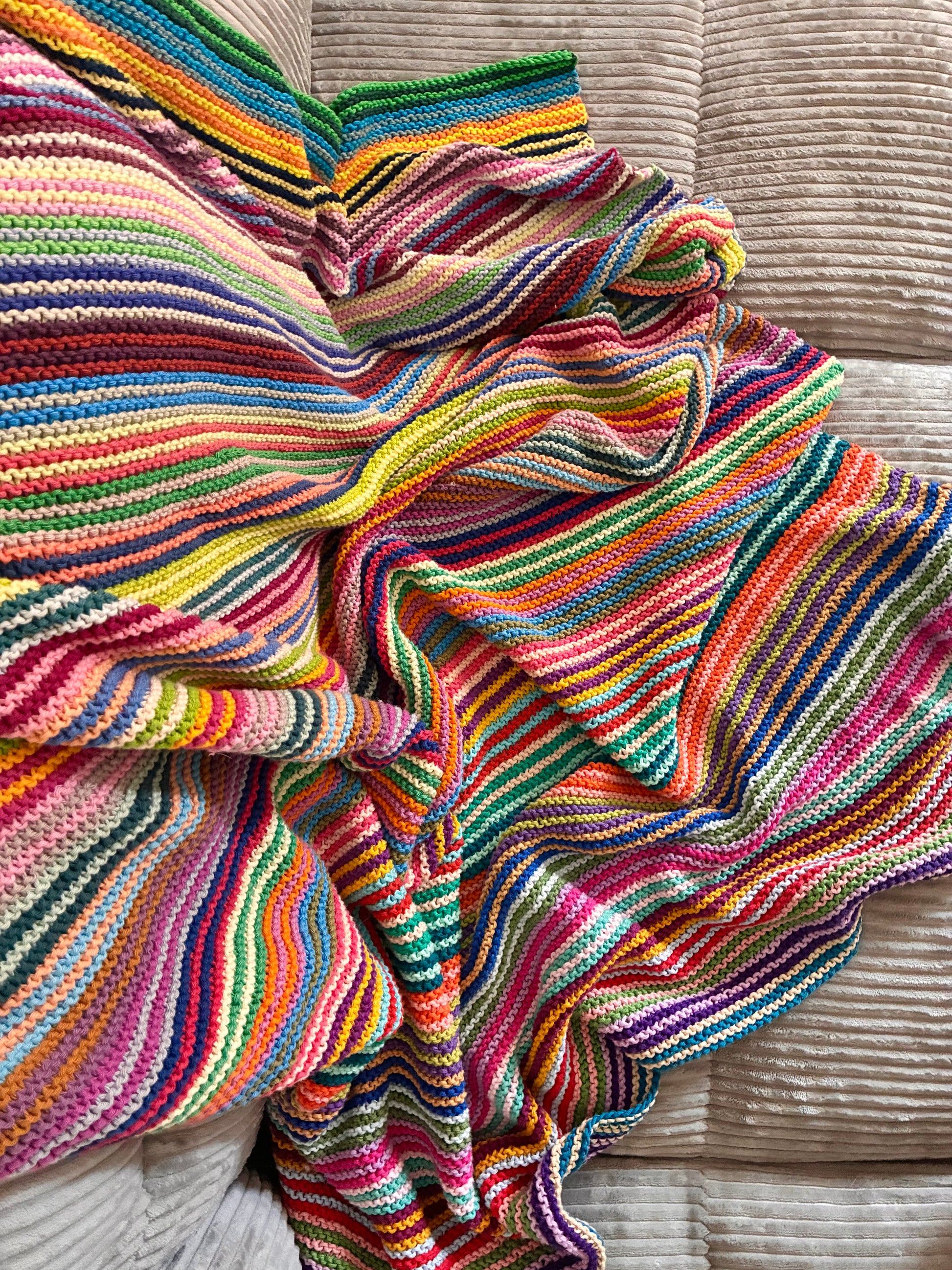 Knit garter stitch blanket using a rainbow of colors in Scheepjes Cahlista yarn