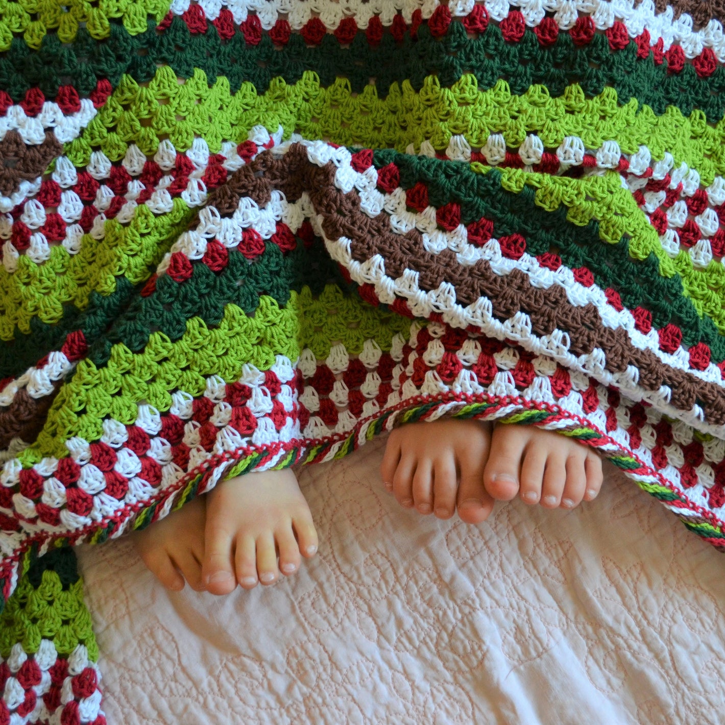 crochet granny stripe blanket in red and white to represent candy canes, greens for christmas and the grinch, and brown for a splash of gingerbread; complete with a twisted crochet candy border