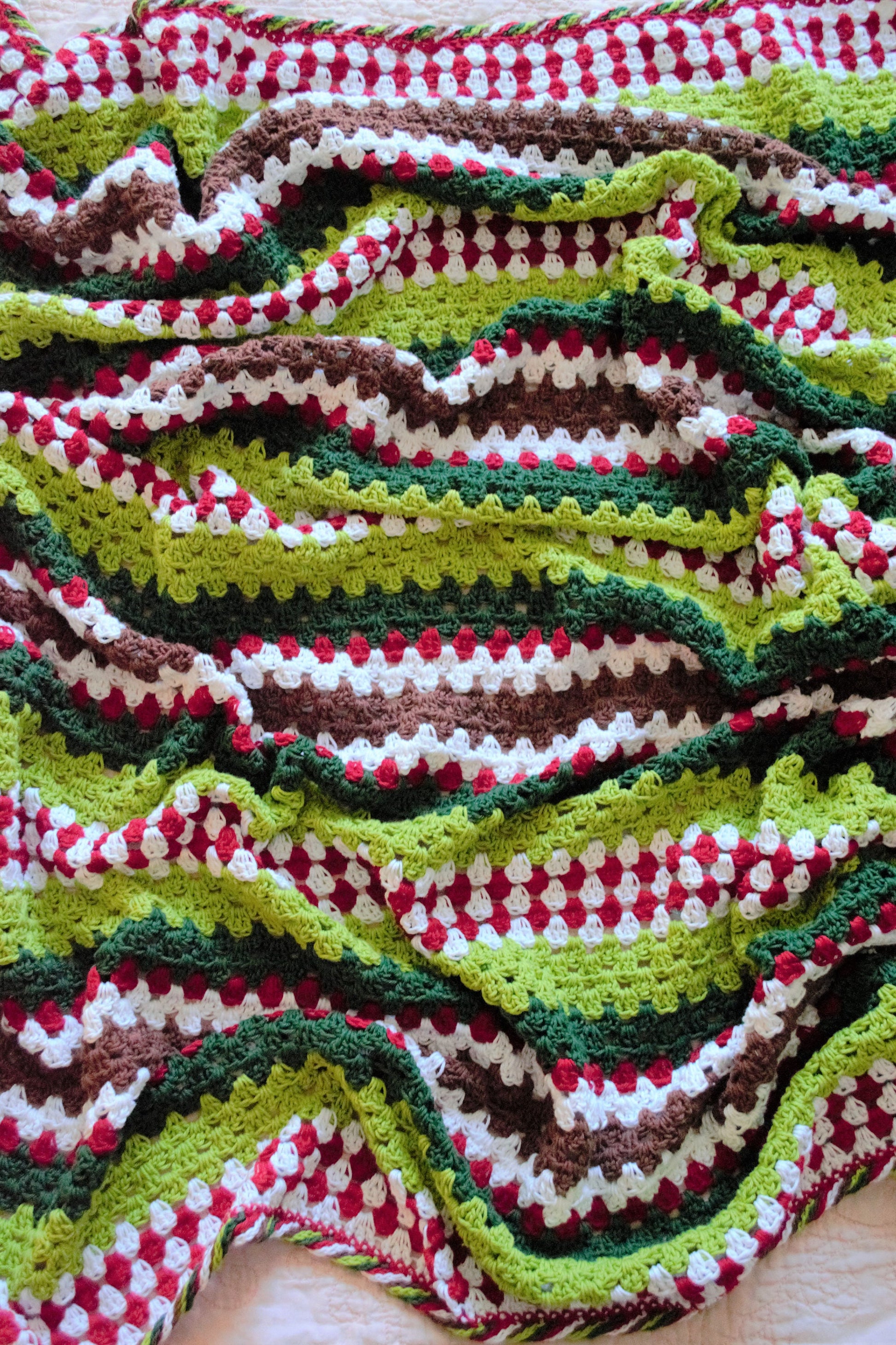 crochet granny stripe blanket in red and white to represent candy canes, greens for christmas and the grinch, and brown for a splash of gingerbread; complete with a twisted crochet candy border