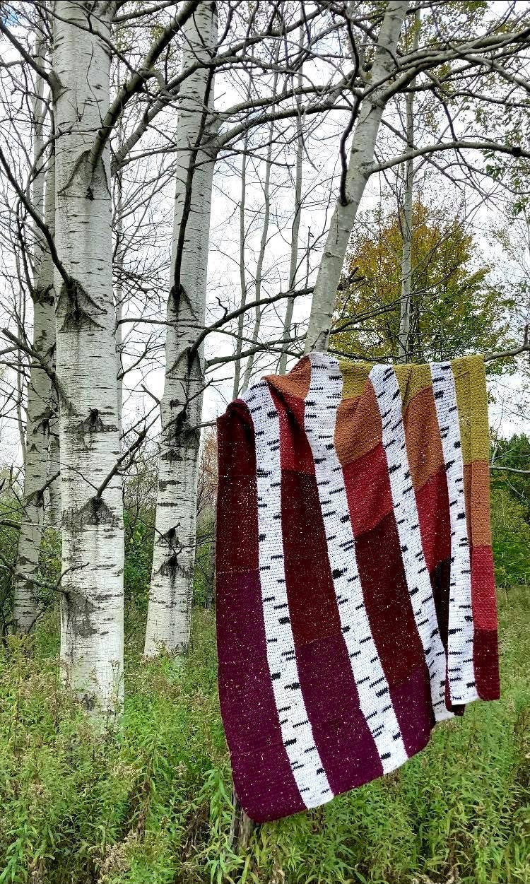 crochet quilt style blanket with alternating columns of colorful textured squares and long vertical birch tree branches